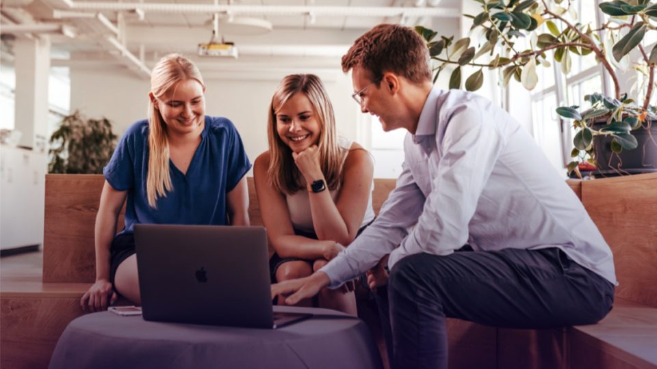Three people sitting at a laptop